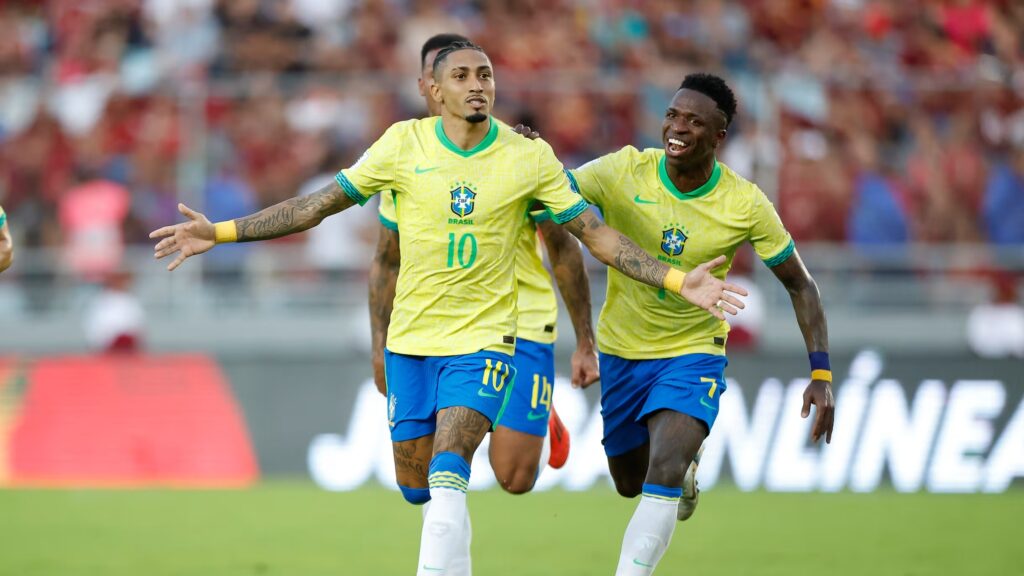 Raphinha e Vinicius Junior celebrando gol do Brasil nas Eliminatórias Copa do Mundo 2026.