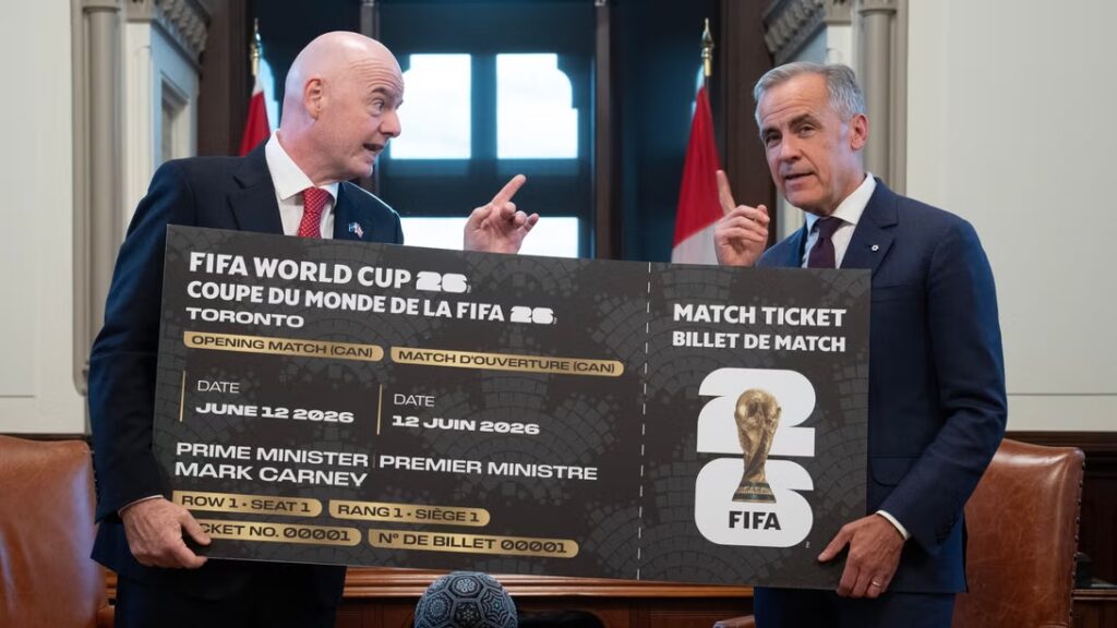 Gianni Infantino e Mark Carney segurando réplica gigante de ingresso da Copa do Mundo ao lado do Primeiro-Ministro do Canadá.