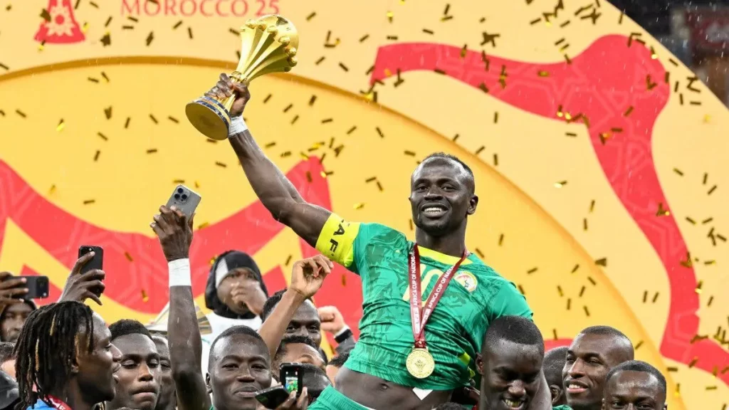 Jogadores de Senegal celebram título da Copa Africana de Nações levantando Sadio Mané com o troféu após vitória sobre Marrocos.