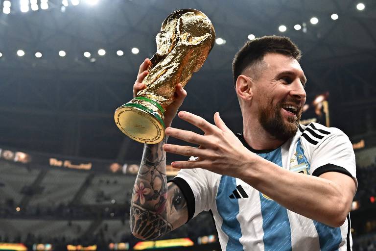 Lionel Messi sorrindo e levantando a taça da Copa do Mundo 2022 nos ombros dos companheiros de equipe após a final contra a França.