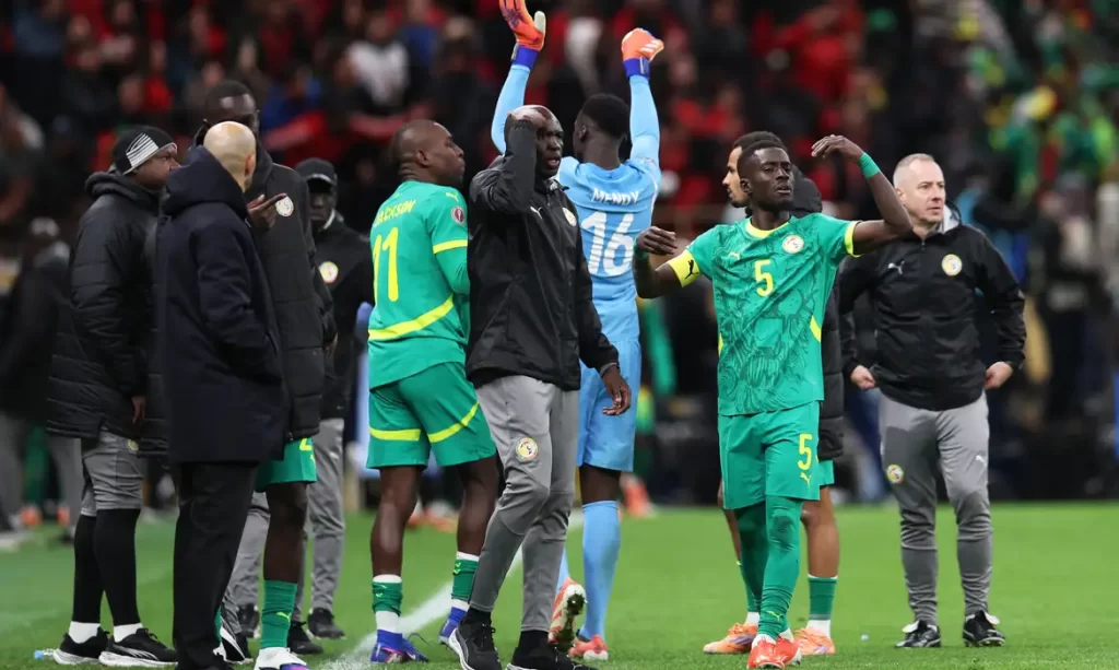 Pape Thiaw e jogadores do Senegal gesticulando para abandonar o campo em protesto contra o árbitro Jean-Jacques Ndala na final da Copa Africana de Nações 2025 contra Marrocos.