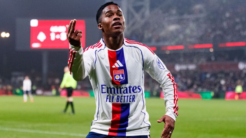 jogador do lyon comemorando gol em partida internacional com torcida ao fundo